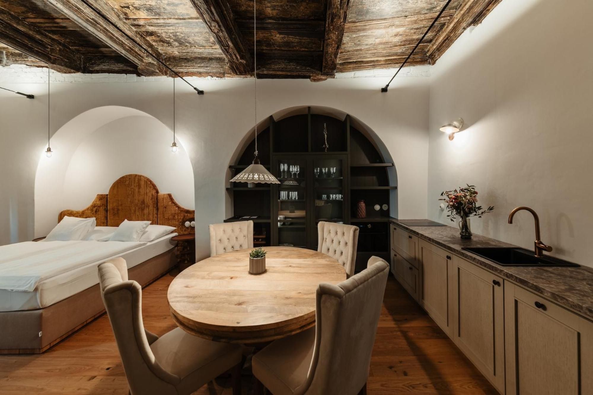 Ein gemütliches Schlafzimmer mit Bett, einem runden Esstisch mit Stühlen, einer Küche mit Spüle und Schränken sowie einer dekorativen Vase.