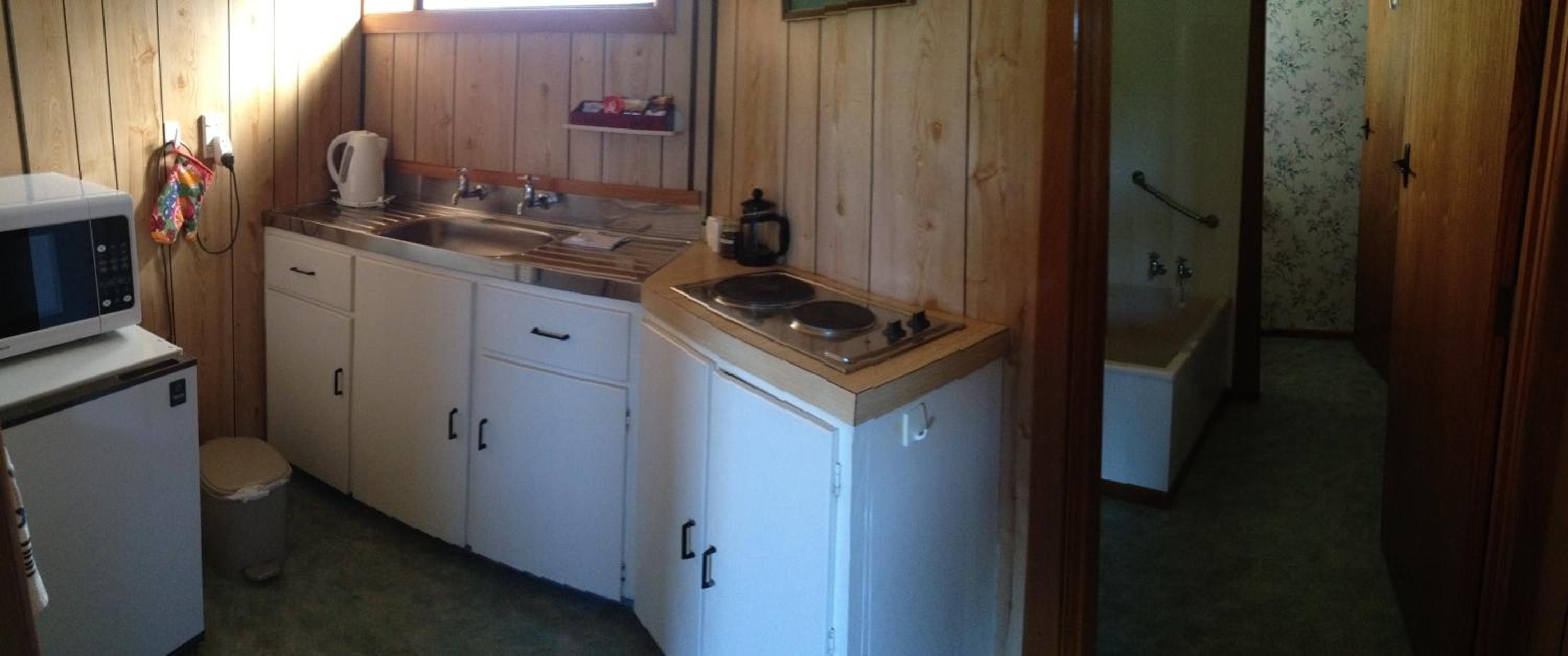 A compact kitchen with a microwave, sink, and stove.