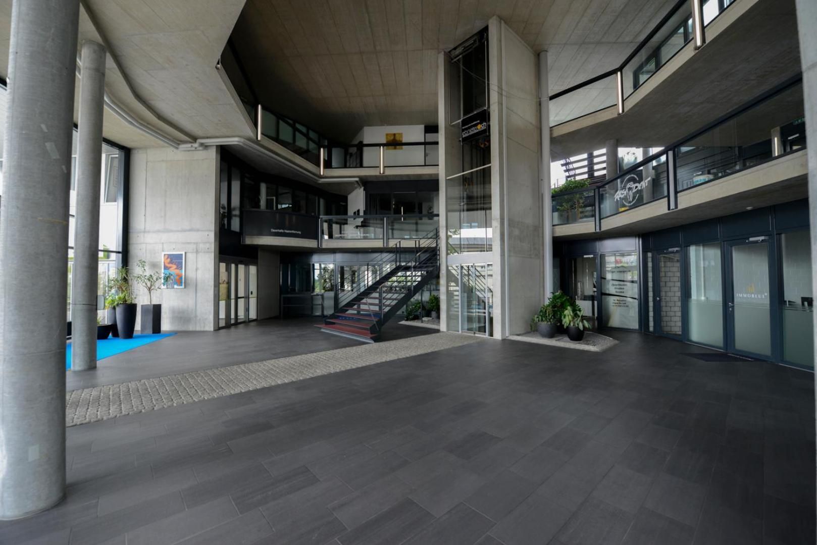 Ein geräumiges Atrium mit einer zentralen Treppe, großen Säulen und einer Empore.
