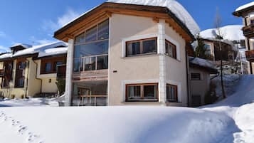 Ein zweistöckiges Gebäude mit verschneitem Dach, großen Fenstern und einem Balkon.