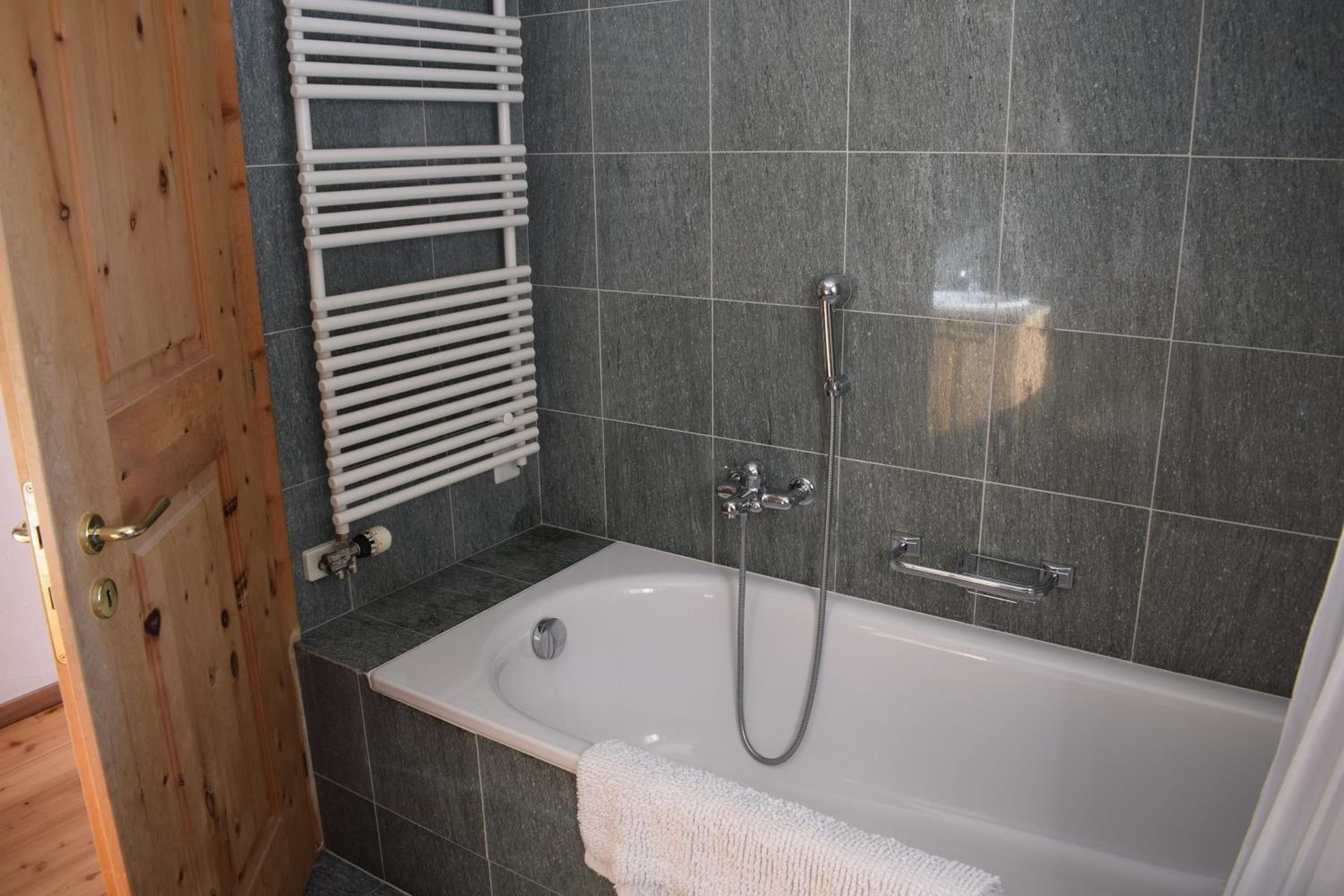 Un bagno con una vasca, una doccia e un portasciugamani.