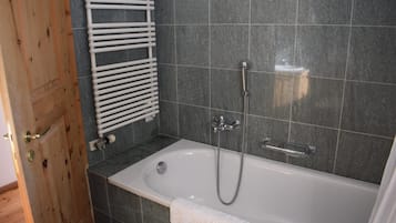 Un bagno con una vasca, una doccia e un portasciugamani.