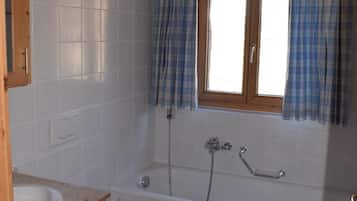 Ein Badezimmer mit einer Badewanne, zwei Waschbecken und einem Fenster mit Vorhängen.
