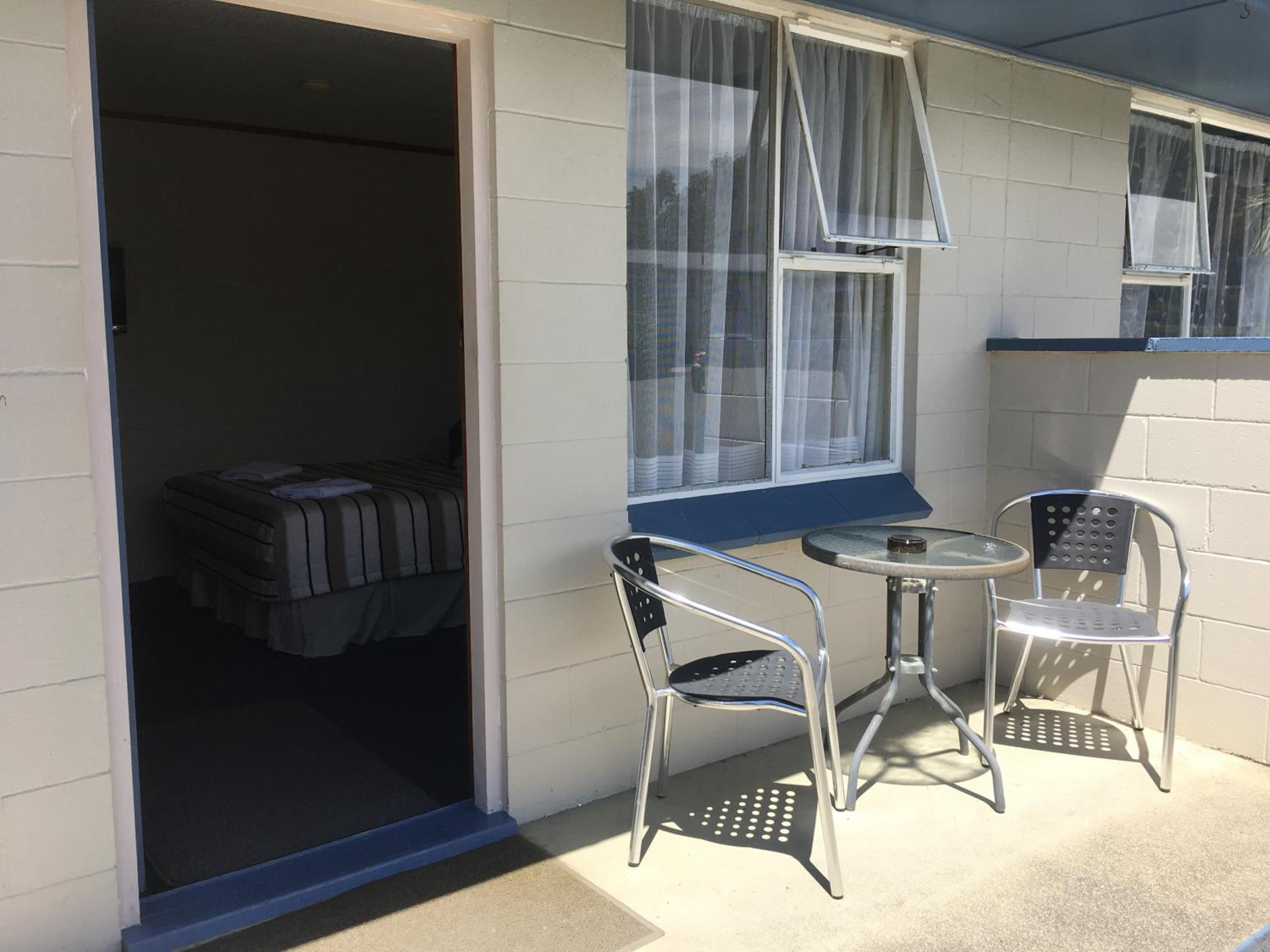 A room with a bed, a small table, and two chairs.