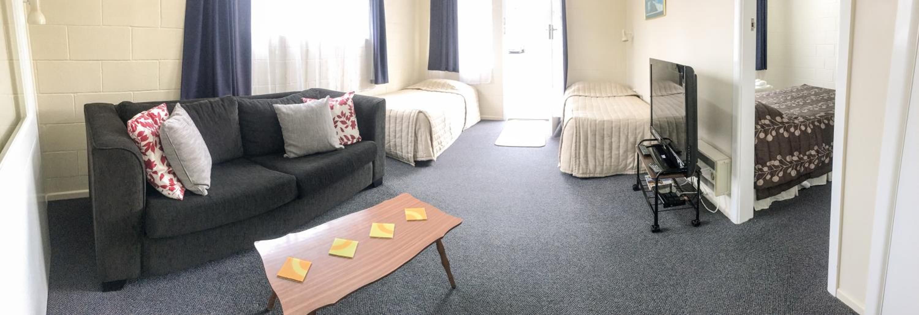 A living room with a sofa, a coffee table, a TV, and a bed.