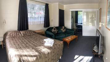 A hotel room with a bed, a sofa, a TV, and a desk.