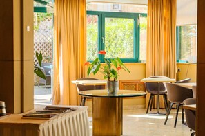 A dining area with a round table, chairs, and a potted plant with red flowers. - Hotel Restaurant Moris (Walferdange)