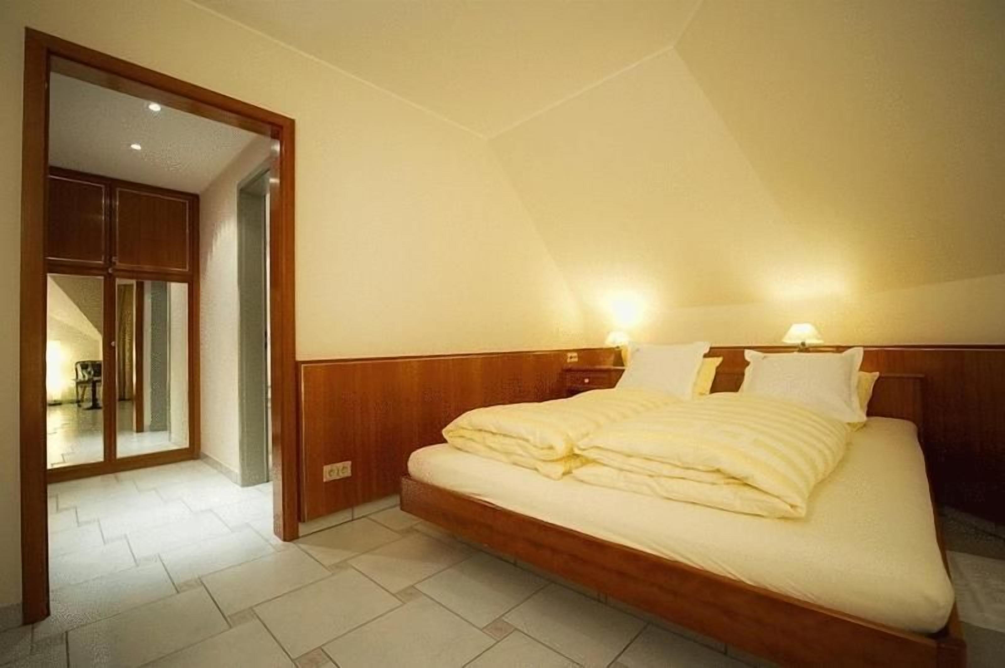 Een slaapkamer met een groot bed, nachtlampjes en een houten hoofdeinde.