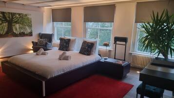 Quarto moderno com cama grande, tapete vermelho, escrivaninha e planta em vaso.