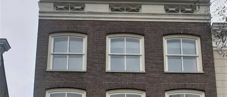 Un edificio de dos pisos con fachada marrón oscuro, ventanas grandes y un llamativo letrero rojo que dice 'La Cubanita'.