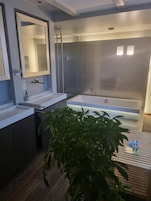 Un baño moderno con lavamanos doble, una bañera grande y un box de ducha.