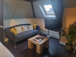 Una sala de estar moderna con un sofá gris oscuro, una mesa de centro de madera y un televisor de pantalla plana grande.