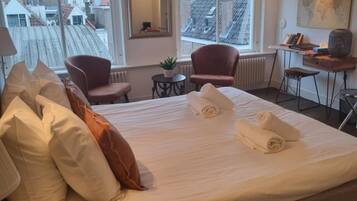 Quarto de hotel com uma cama grande, uma escrivaninha, uma cadeira e vista para a paisagem urbana.