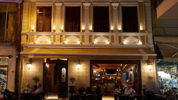 Een gebouw met twee verdiepingen, een balkon, een terras en een restaurantinrichting.