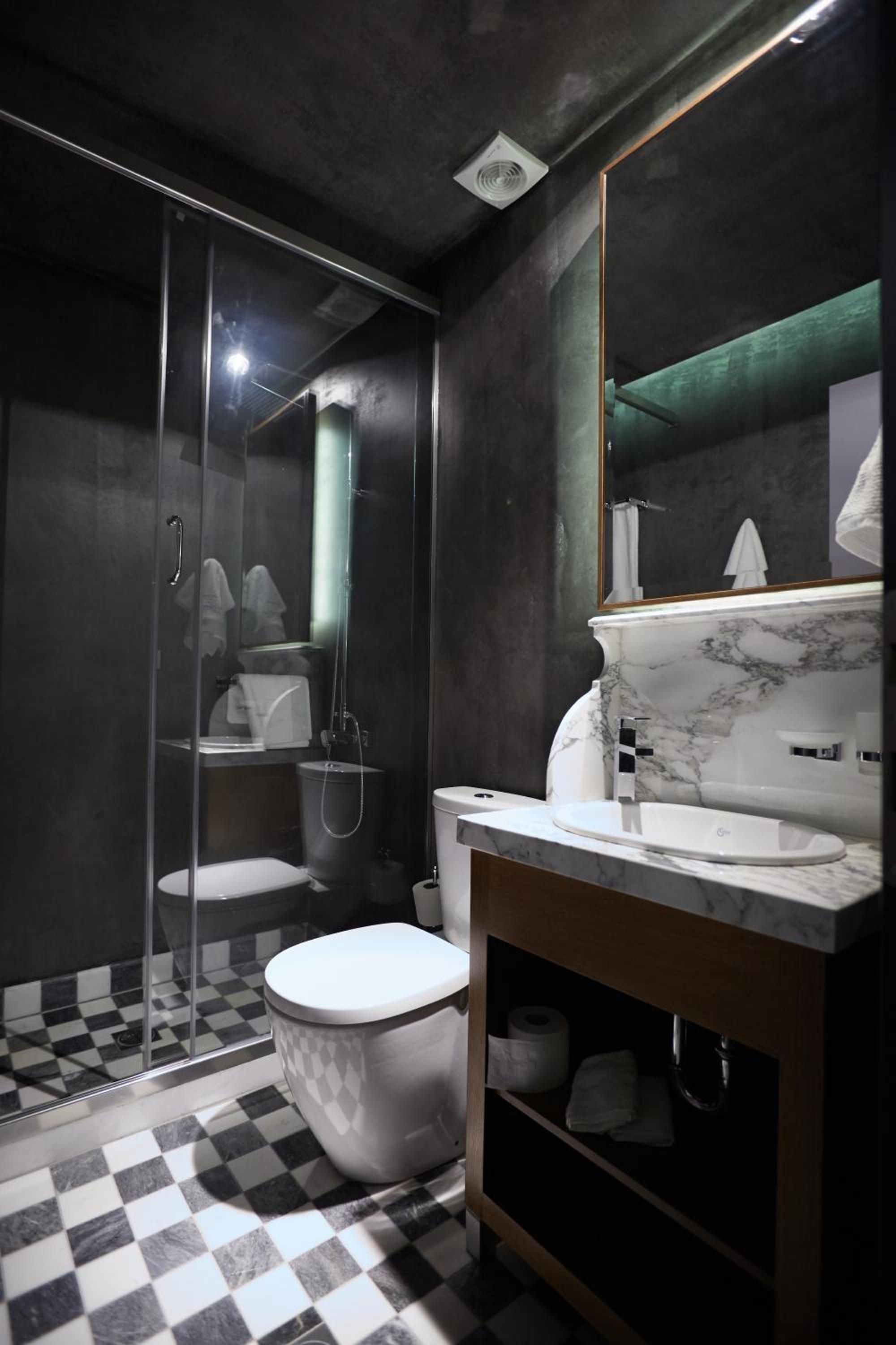 Un baño moderno con cabina de ducha de vidrio, inodoro blanco y lavabo de mármol.