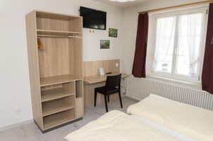 Una habitación con cama, escritorio, silla, armario y radiador.