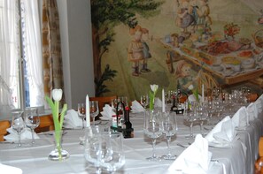 A dining table set with multiple wine glasses, a vase with a single white flower, and a bottle of sauce. - Speiserestaurant Traube (Küttigen)