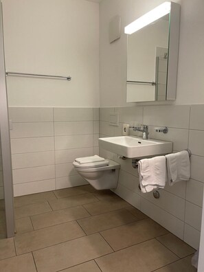 Un baño con inodoro, lavamanos y espejo.