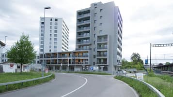 Ein mehrgeschossiges Gebäude mit Balkonen, einem Parkschild und einer gewundenen Straße.