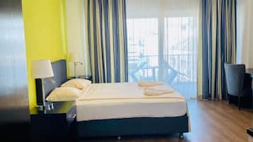 Ein Hotelzimmer mit Bett, Schreibtisch, Stuhl und Blick ins Freie.