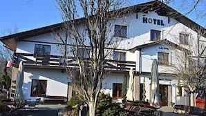Un hotel amb façana blanca, moltes finestres i un balcó.
