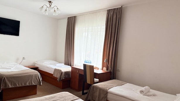 Habitació d'hotel amb dos llits individuals, una taula de treball, una cadira i un televisor fixat a la paret.