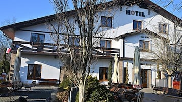 A hotel with a white exterior, multiple windows, and a balcony.