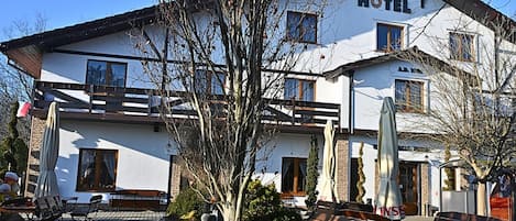 Un hotel con fachada blanca, numerosas ventanas y un balcón.