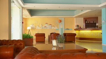 A hotel lobby with a seating area, a reception desk, and decorative wall art.