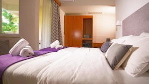 A hotel room with a bed, pillows, a nightstand, a wardrobe, and a window with curtains. - Antikyra Beach Hotel (Distomo-Arachova-Antikyra)