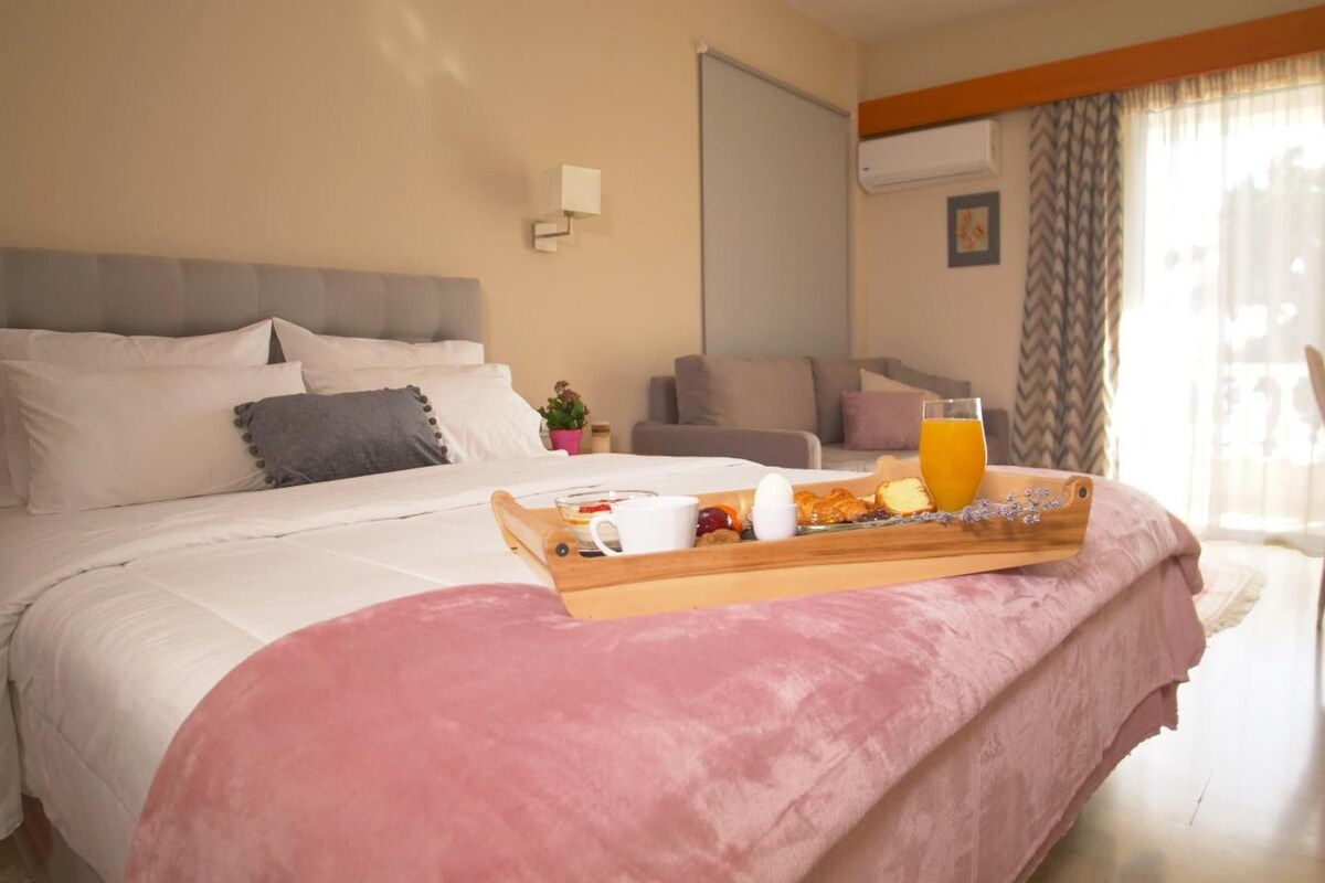 A hotel room with a bed, a breakfast tray, a sofa, and a window with curtains.