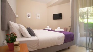 A hotel room with a bed, a television, and a window with a view of greenery. - Antikyra Beach Hotel (Distomo-Arachova-Antikyra)