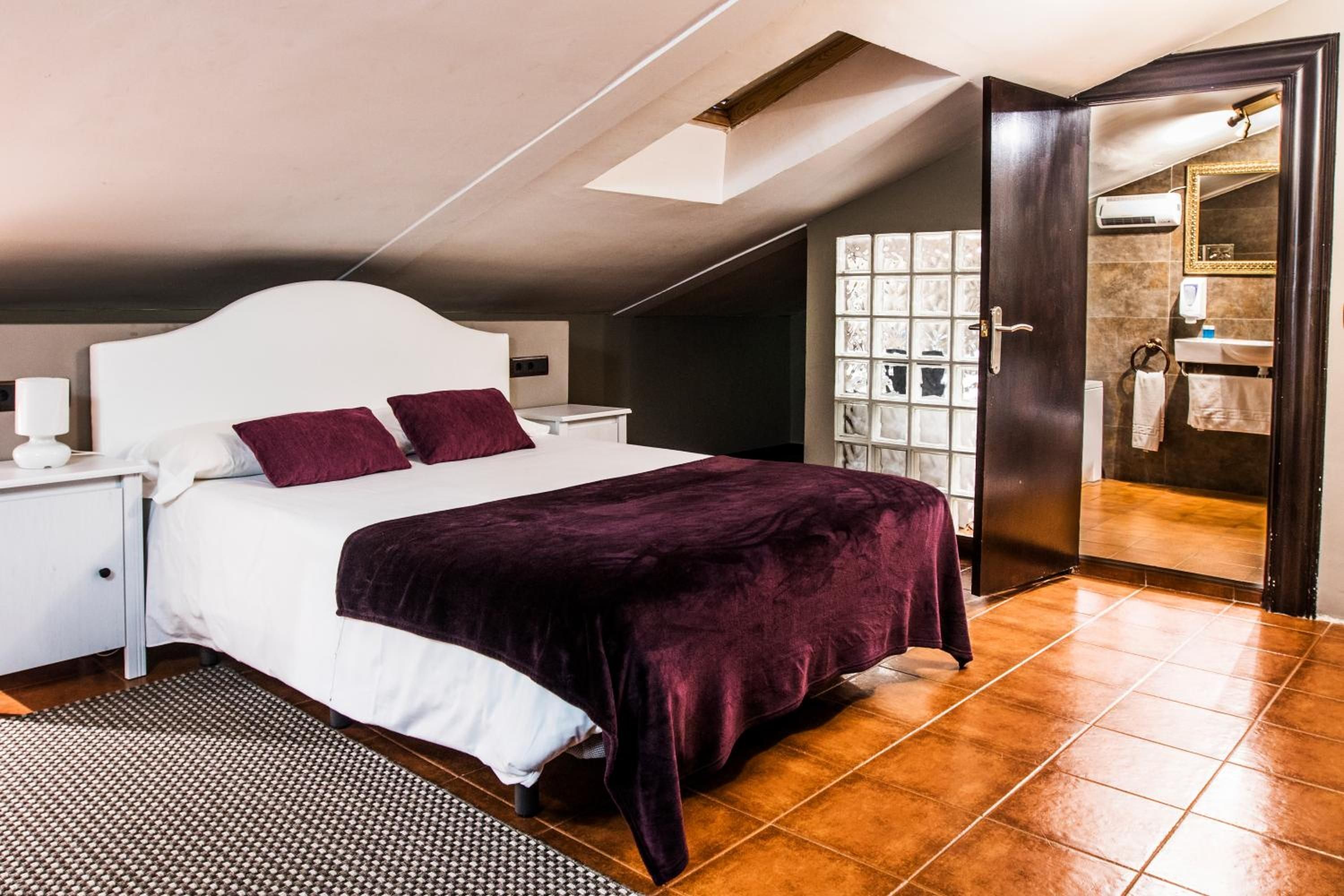 A bedroom with a bed, nightstands, a window, and a door leading to a bathroom.