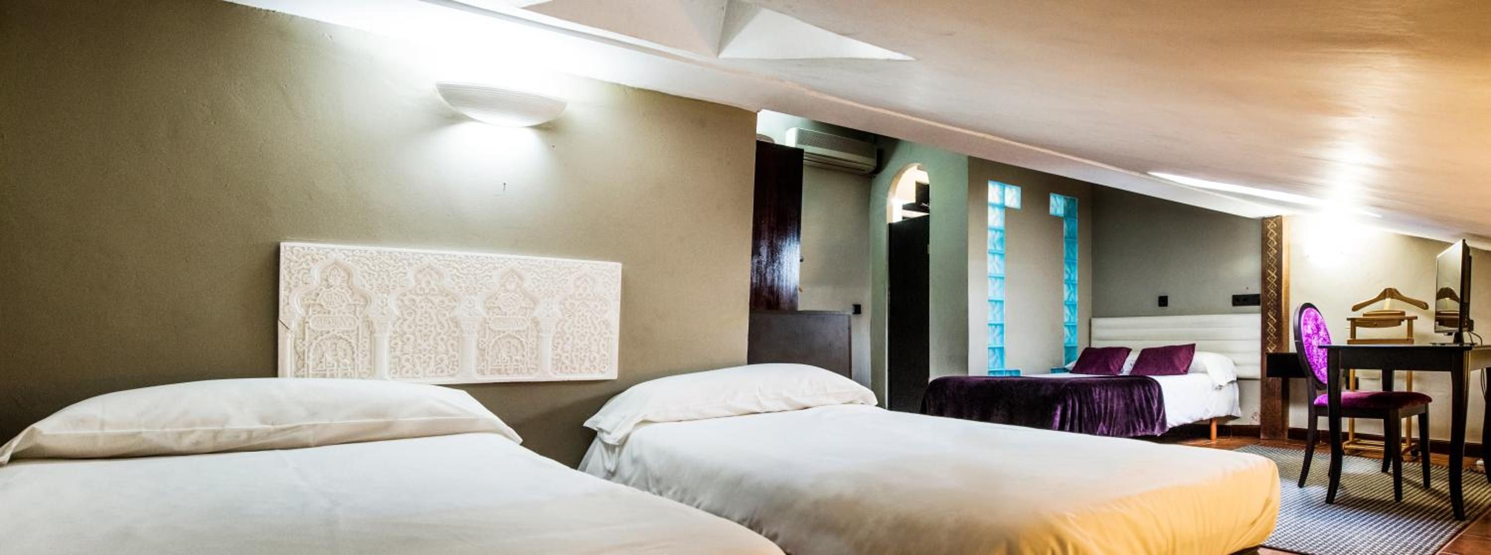 Habitación de hotel con dos camas, un escritorio, una silla y un espejo.