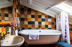 A bathroom with a freestanding bathtub, a sink, and a mirror.