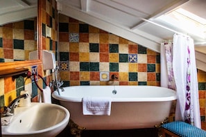 A bathroom with a freestanding bathtub, a sink, and a mirror.