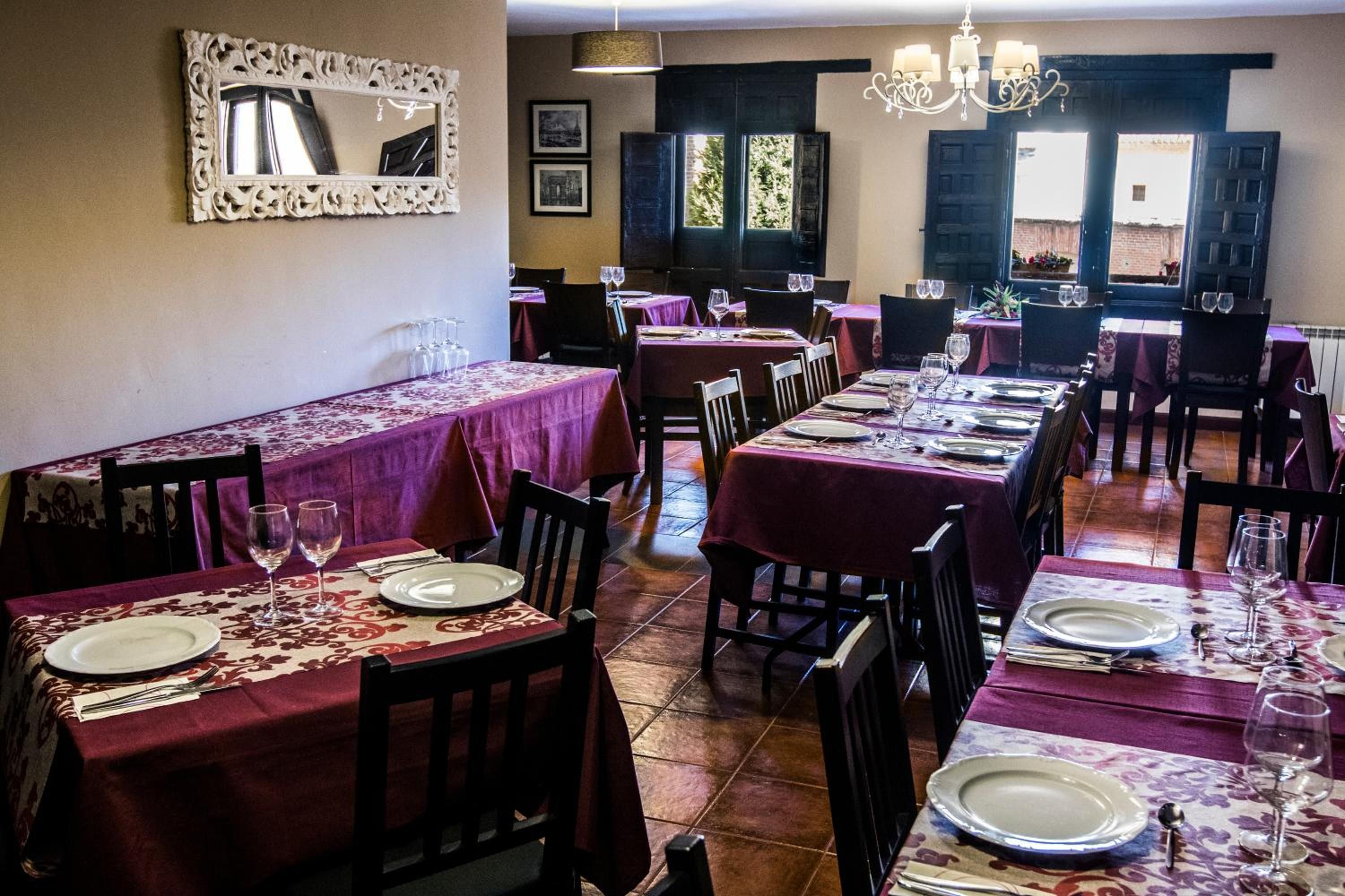 Un restaurante con varias mesas dispuestas para comer, con un diseño de mantel consistente y un clásico candelabro.
