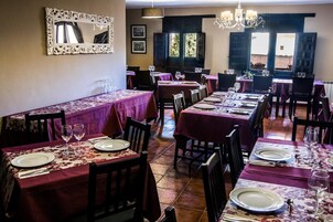 A restaurant with multiple tables set for dining, featuring a consistent tablecloth pattern and a classic chandelier.
