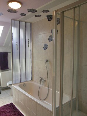 A bathroom with a bathtub, a shower, and a glass-enclosed shower area. - Land Stil (Hagen im Bremischen)