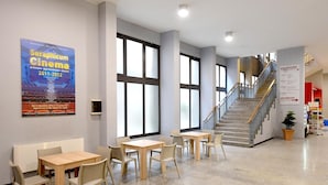 A spacious indoor area with a staircase, seating tables, and a poster on the wall.