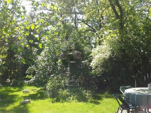 A garden with a table and chairs, surrounded by lush greenery and trees. - Akacja Pokoje Go Ocinne (Kraków)