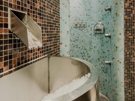 Un baño con un lavabo grande, paredes con azulejos y una zona de ducha.