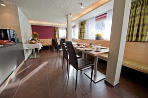 Un comedor de hotel con barra libre, una máquina de café y una ventana con cortinas.