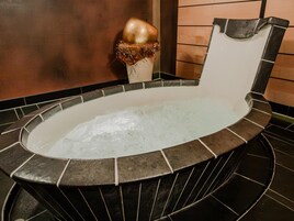 A hot tub with a stone exterior and a wooden wall in the background.