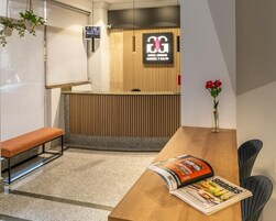 Zona de recepción con diseño de paneles de madera, un banco, una revista sobre la mesa y un florero con flores.