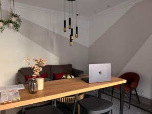 Un comedor moderno con una mesa de madera, una computadora portátil y un sofá.