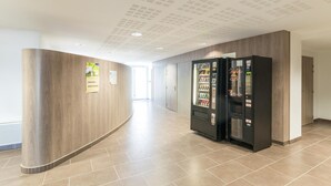A hallway with a wooden wall, a vending machine, and a door at the end. - City Rv Sidence Nantes La Chantrerie (Nantes)