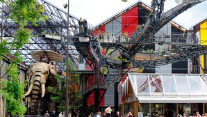 A public square with a large elephant sculpture, a modern building with red and gray panels, and outdoor seating for cafes. - City Rv Sidence Nantes La Chantrerie (Nantes)