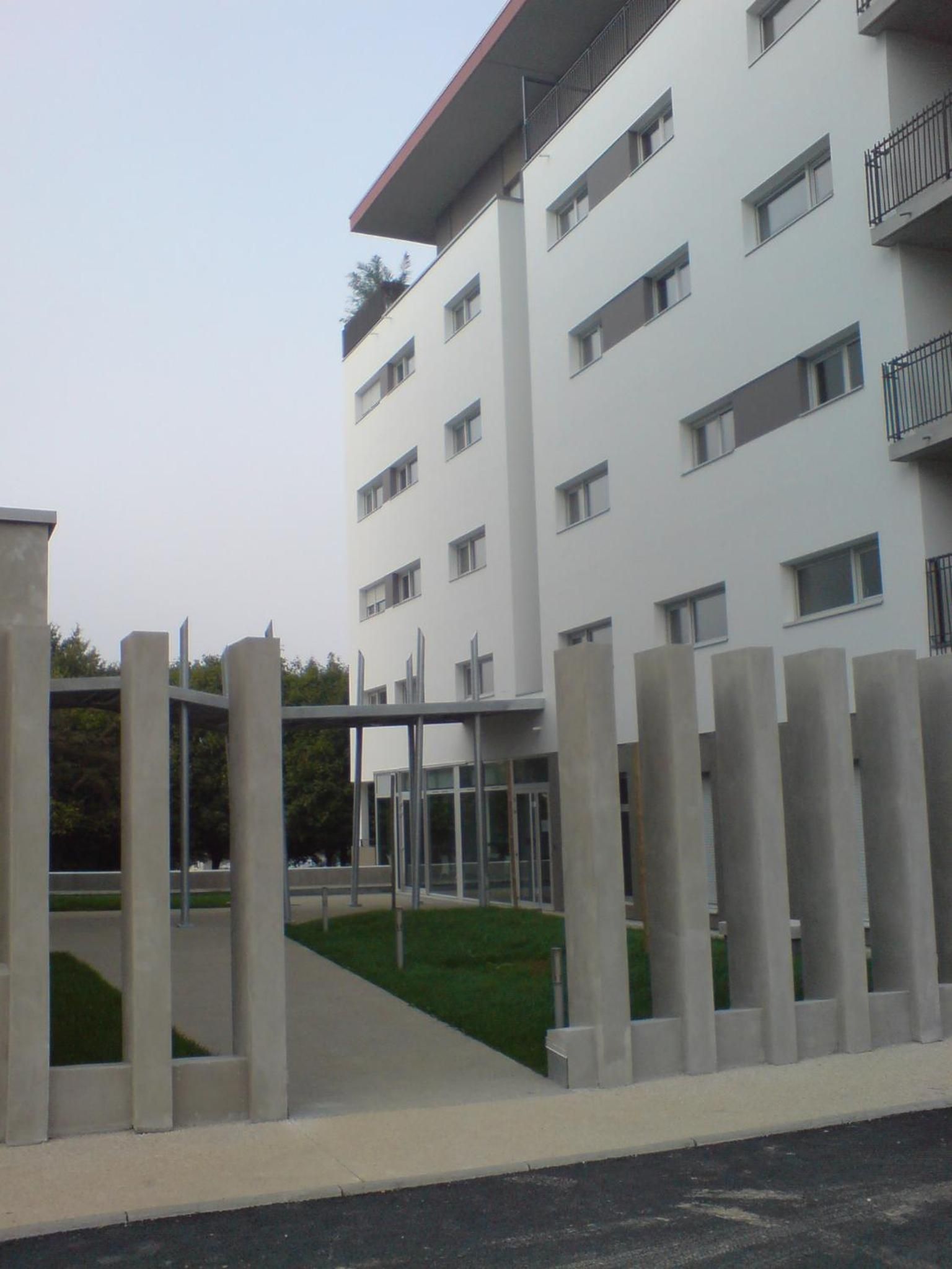 A multi-story building with a flat facade, rectangular windows, and a balcony on the upper floors.