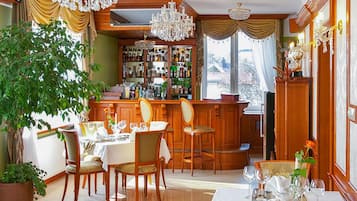 A dining area with a bar, wooden furniture, and a large potted plant.